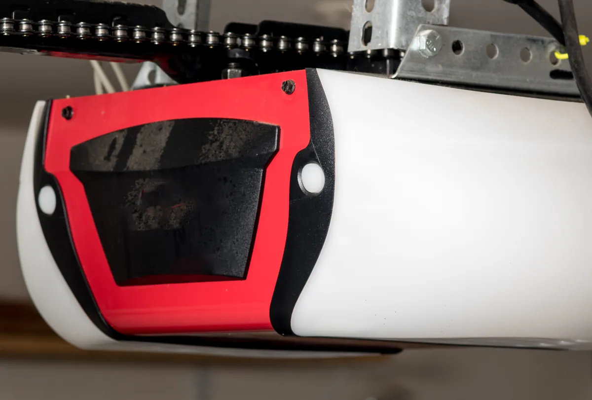 Red and white garage door opener unit mounted under its chain rail
