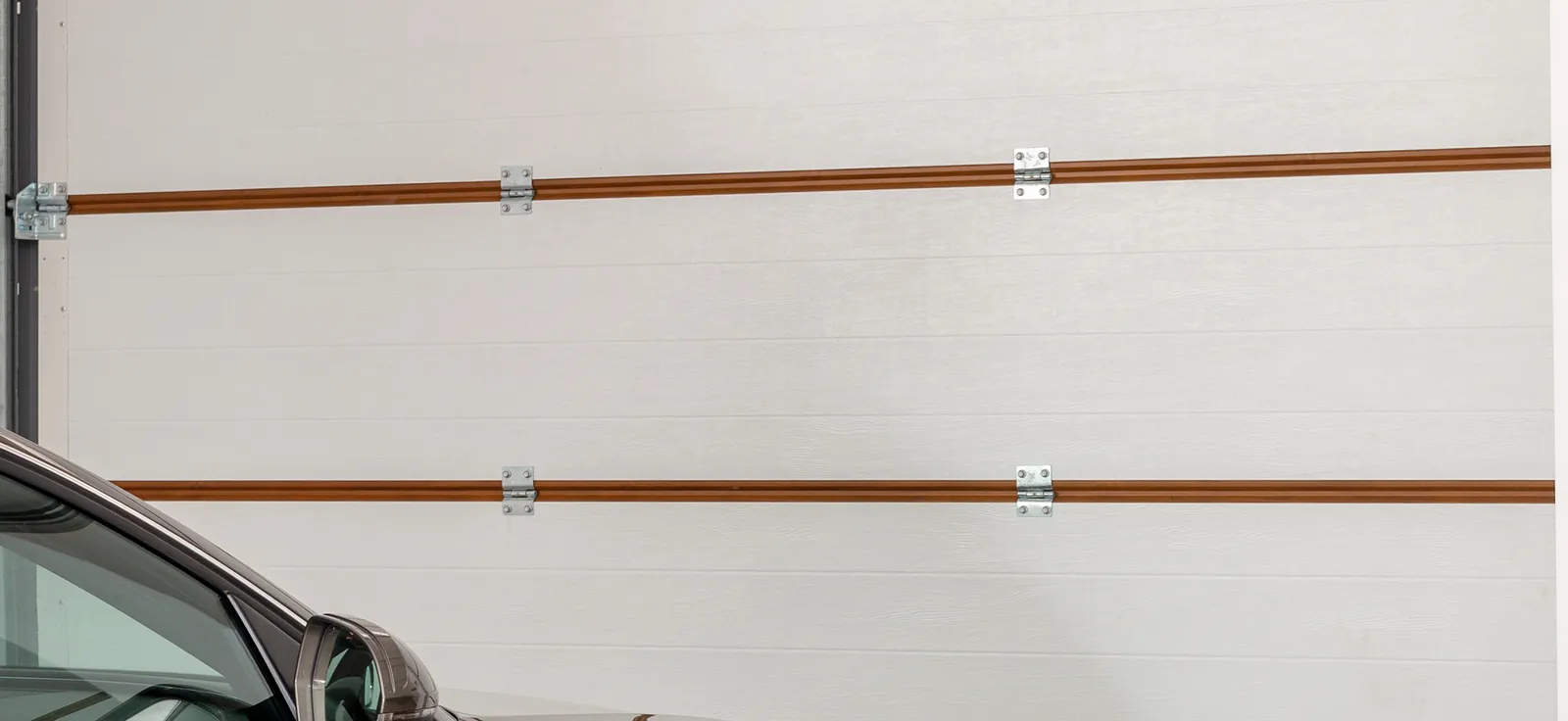 Upper sections of a white sectional door, joined by hinges along wood-tone stripes