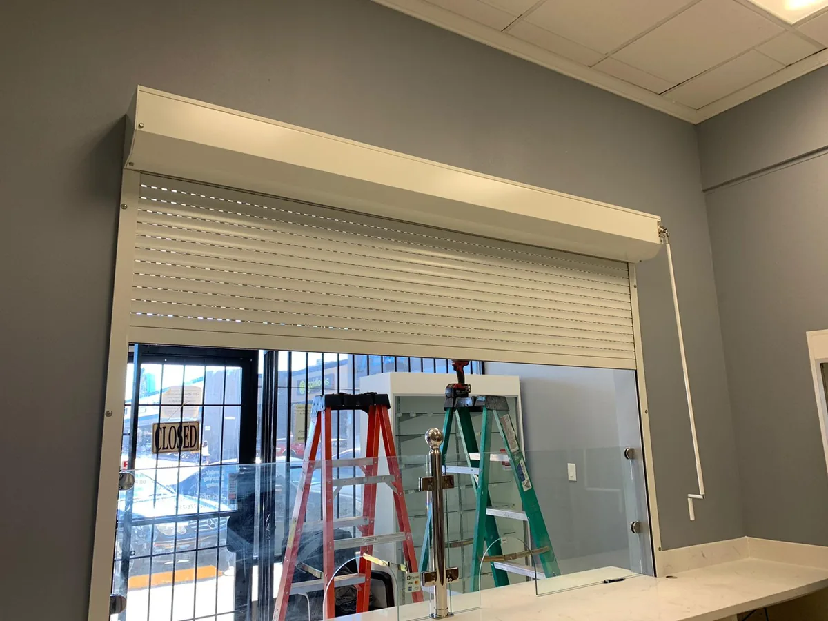 Counter-top rolling shutter over a pickup window, ladders set up behind the glass