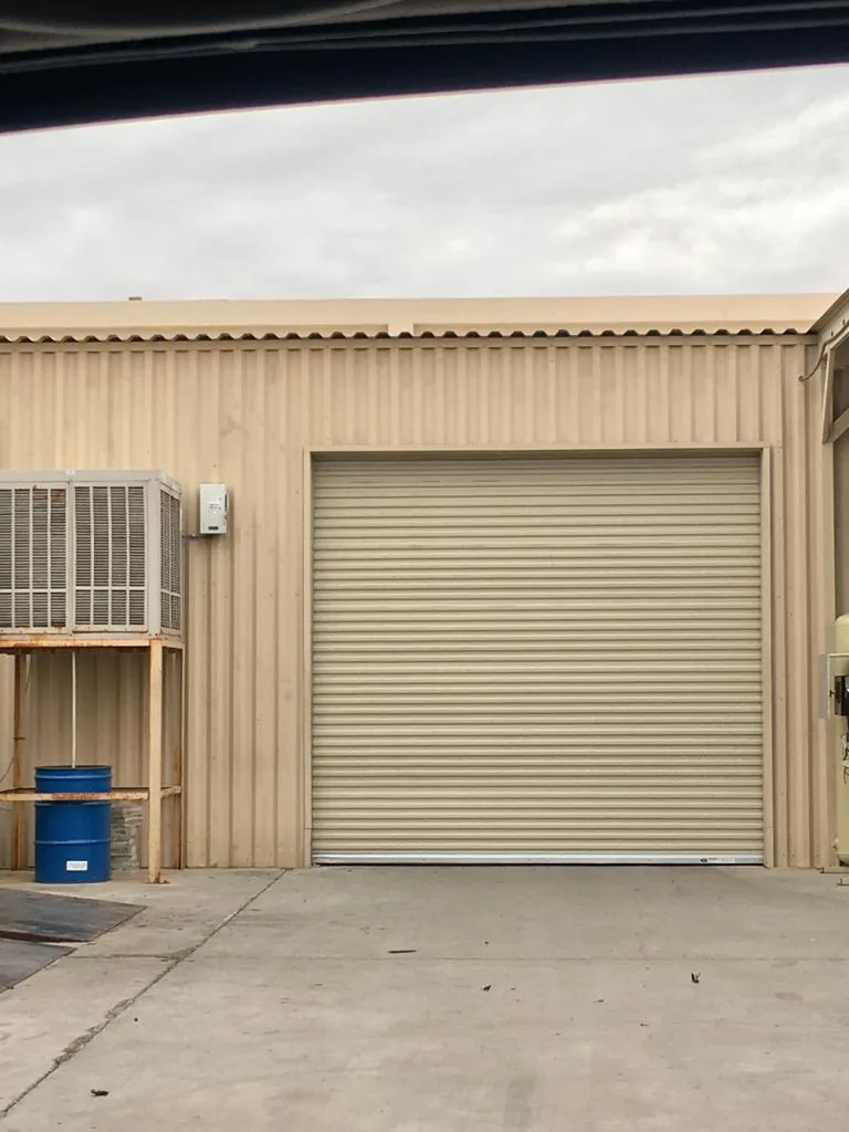 Tan roll-up door on a corrugated metal warehouse building